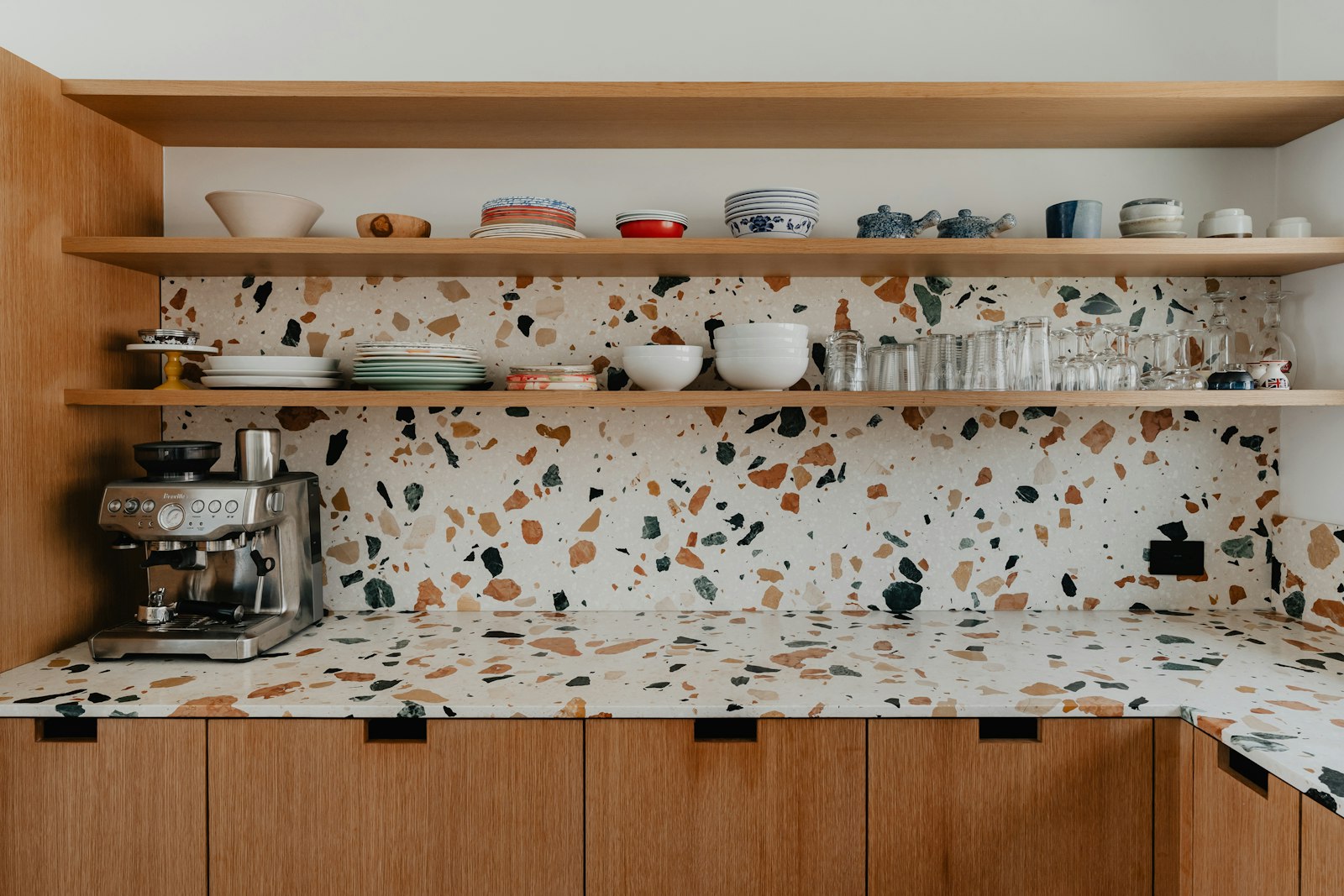 Warm kitchen with open shelving, tableware, and a coffee maker