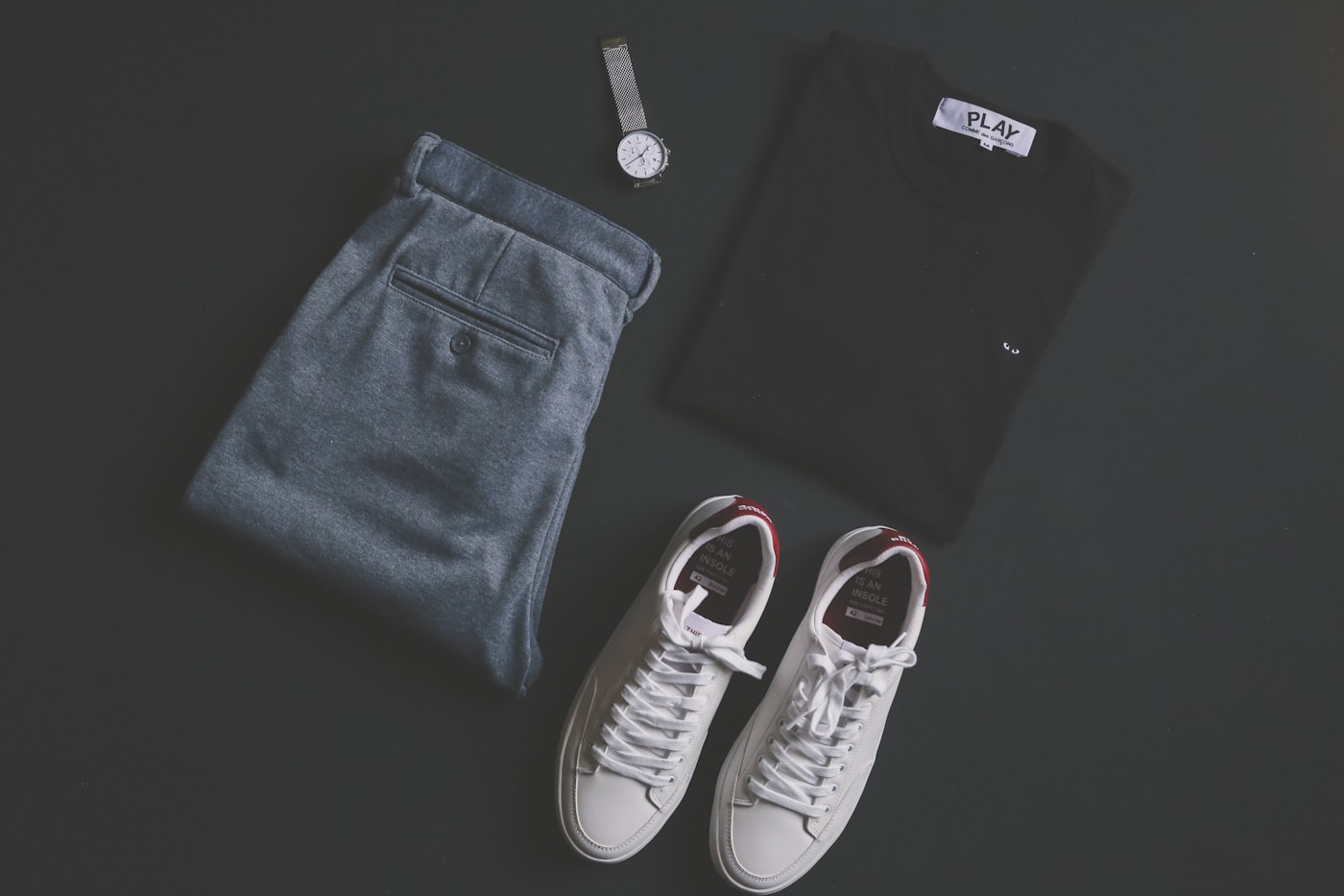 Coordinated outfit, accessories, and sneakers arranged on a dark surface